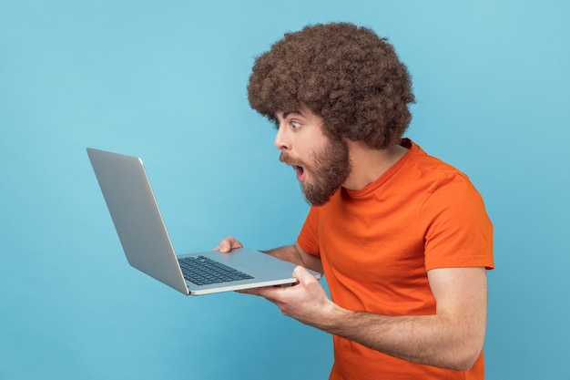 Hombre haciendo trabajo independiente en la computadora portátil escribiendo correo electrónico navegando por Internet mirando sorprendido la pantalla de la computadora portátil