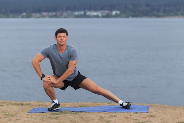 Hombre haciendo yoga al aire libre. Joven practicando ejercicio físico de yoga al aire libre en el hermoso mar. Meditación y relajación