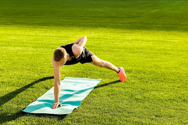 Foto un hombre haciendo yoga en una alfombra verde.