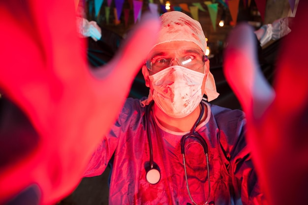 Hombre hansome emocionado vestido como un doctor espeluznante en la fiesta de Halloween. Hombre adulto celebrando halloween.