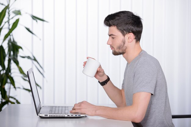 Hombre hermoso joven de la barba que trabaja en su lugar de trabajo.