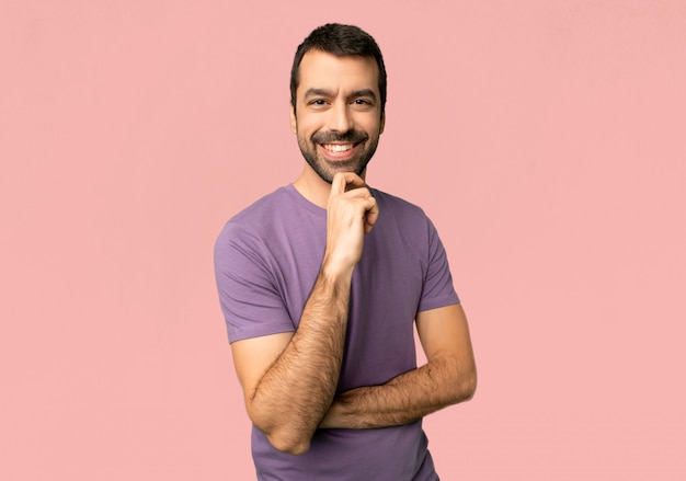 Hombre hermoso que sonríe y que mira al frente con la cara confiada en fondo rosado aislado