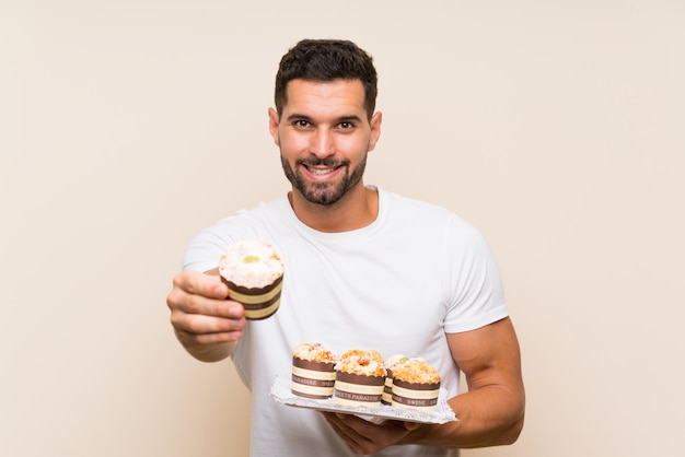 Hombre hermoso que sostiene la torta del panecillo sobre aislado