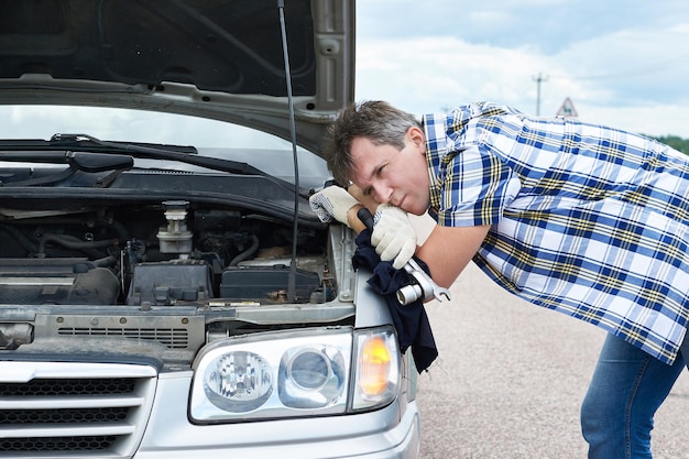 Foto hombre con herramientas cerca de auto roto