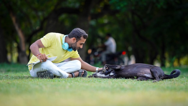 Un hombre en la hierba haciendo dormir al perro.