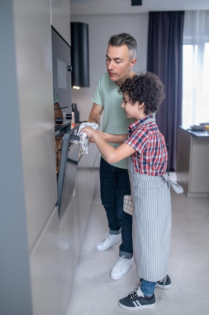 Hombre con hijo abriendo horno en casa