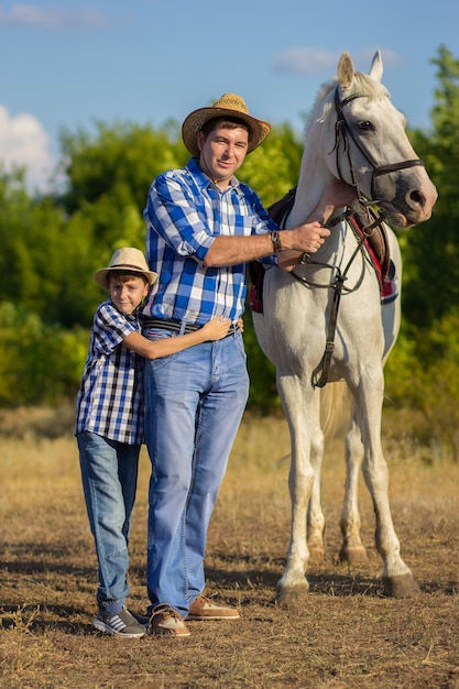 El hombre del hijo con sombreros en un paseo con un caballo blanco.