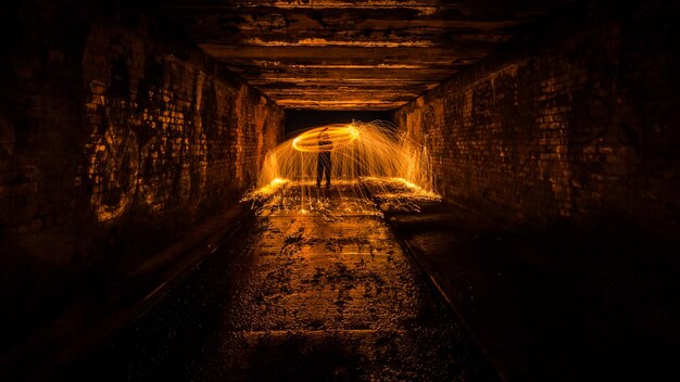 Foto hombre hilando lana de alambre iluminada en el túnel por la noche