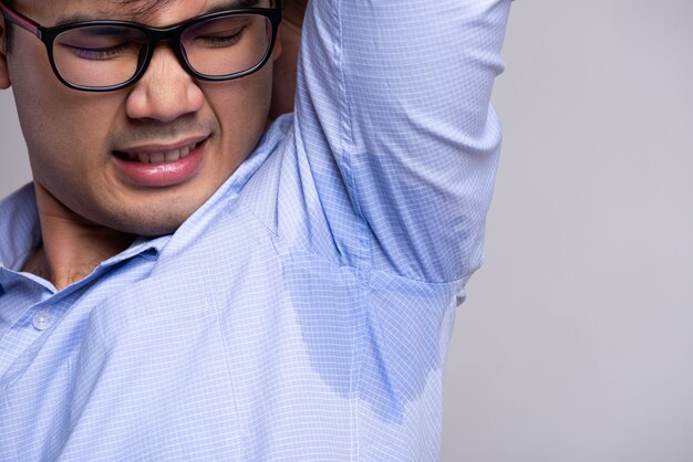 Hombre con hiperhidrosis sudando en su ropa. Concepto de salud.