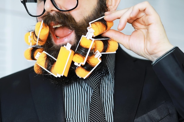 Hombre hipster alegre con rulos en la barba Hombre sorprendido con gafas mira al frente