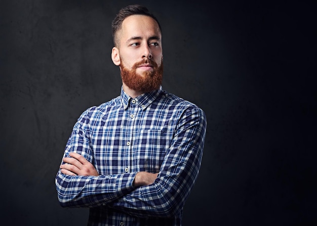 Hombre hipster barbudo pelirrojo pensativo con los brazos cruzados, vestido con una camisa de lana azul.