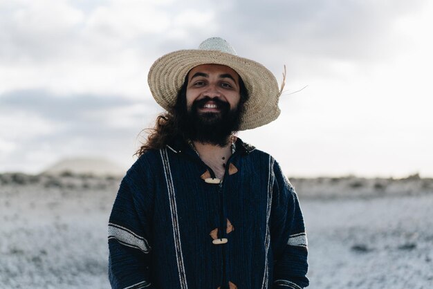 Hombre hipster barbudo sonríe mientras mira a la cámara