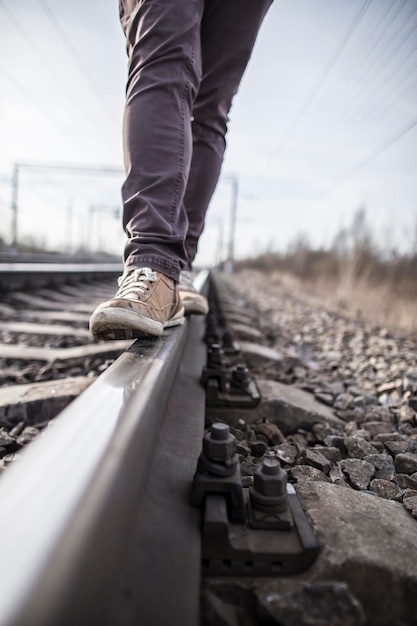 Hombre hipster camina con confianza a lo largo de los rieles del ferrocarril