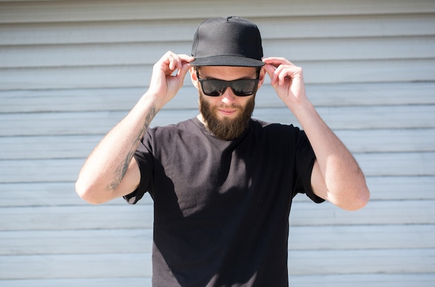 Hombre hipster con camiseta negra y un sombrero negro con espacio para logo