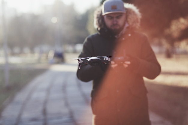 Hombre hipster con drone volador en el parque