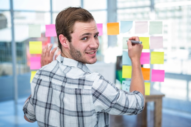 Hombre hipster escribiendo en post-it en la oficina