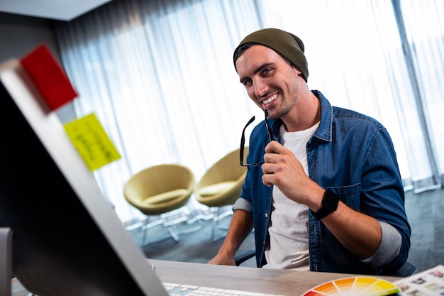 Hombre hipster con gafas mientras trabajaba en el escritorio de la computadora