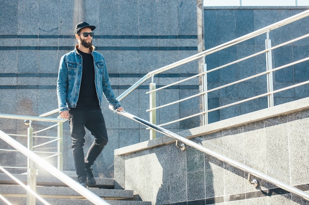 Hombre hipster con gafas de sol y una gorra negra en una ciudad