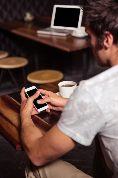 Hombre hipster con smartphone mientras bebe café