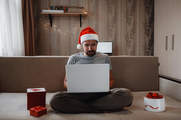 Un hombre hipster con una taza roja sentado en casa en Navidad