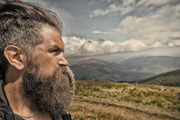 Hombre hipster viajero con retrato de barba y bigote en la montaña