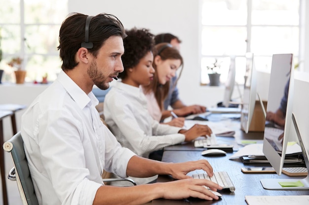 Hombre hispano con auriculares trabajando en la computadora en la oficina