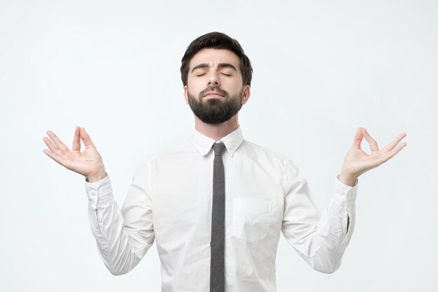 Hombre hispano barbudo concentrado con meditaciones intenta relajarse después de un duro día de trabajo