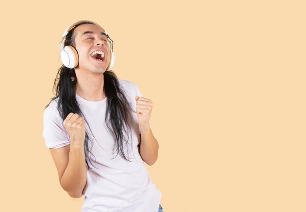 hombre hispano cantando con auriculares fondo beige