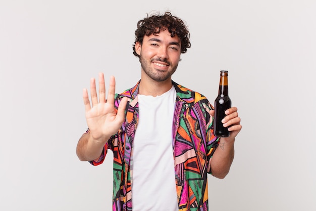 Hombre hispano con cerveza sonriendo feliz y alegremente, saludando con la mano, dándote la bienvenida y saludándote, o despidiéndose