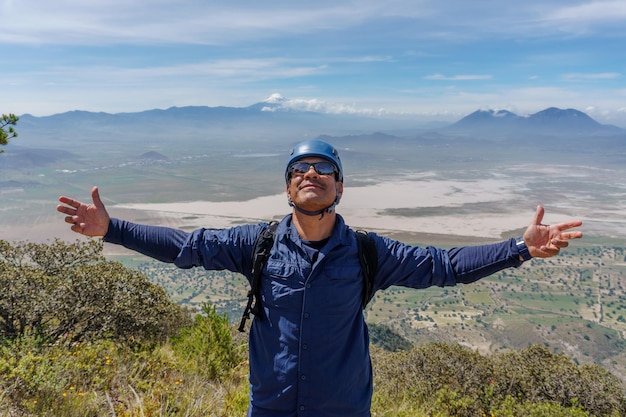 Hombre hispano, en la cima de una montaña, con, brazos abiertos