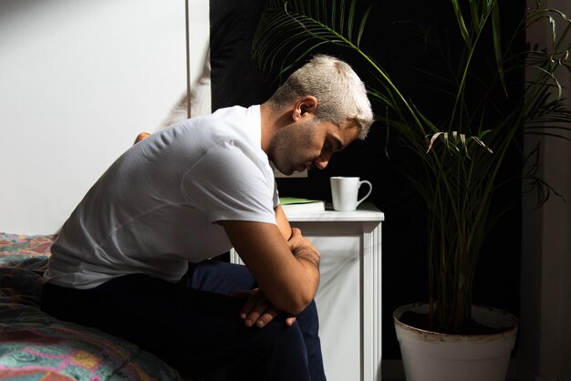 Hombre hispano deprimido sentado en su cama pensando en sus problemas Concepto de salud mental