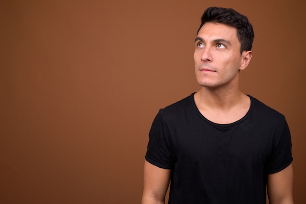Hombre hispano guapo joven en pared marrón