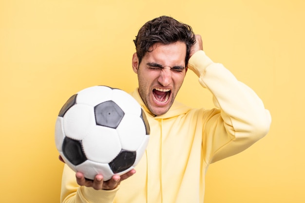 Hombre hispano hermoso joven con un balón de fútbol