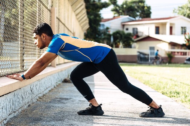 Foto hombre hispano joven atleta haciendo estiramientos en todo el cuerpo antes de entrenar