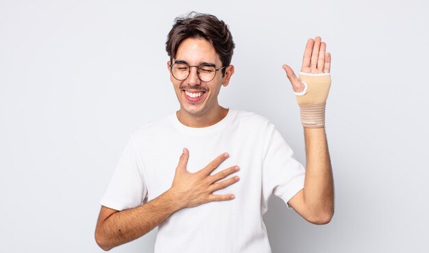 Hombre hispano joven que se ríe a carcajadas de una broma hilarante. concepto de vendaje de mano