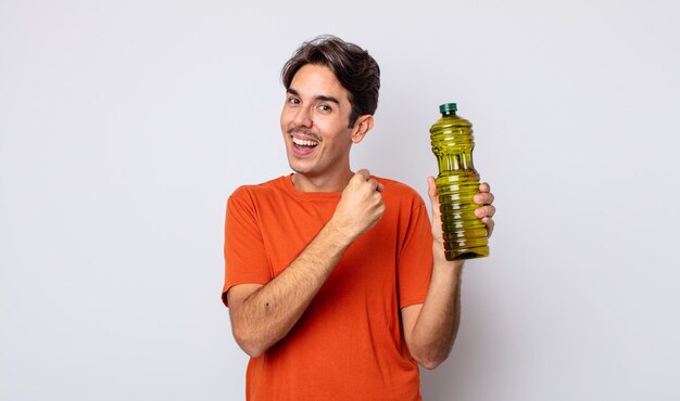 Foto hombre hispano joven que se siente feliz y enfrenta un desafío o celebrando. concepto de aceite de oliva