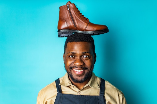 Hombre hispano latino con delantal negro que muestra zapatos de cuero marrón con fondo azul de estudio