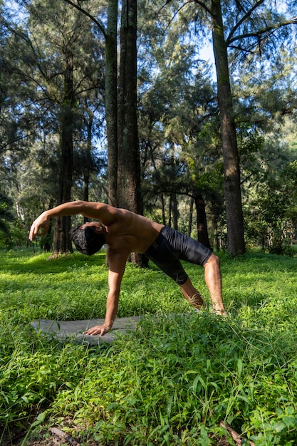 Hombre hispano y latino meditando en medio de un bosque recibiendo rayos de sol piel morena mexico