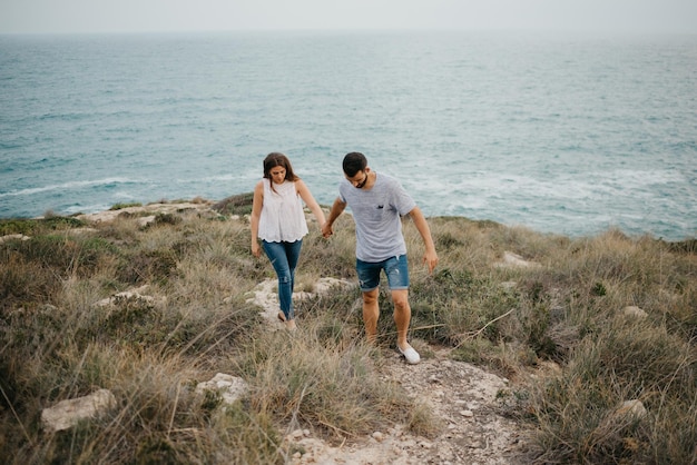 Un hombre hispano y su novia latina caminan cerca del mar en España