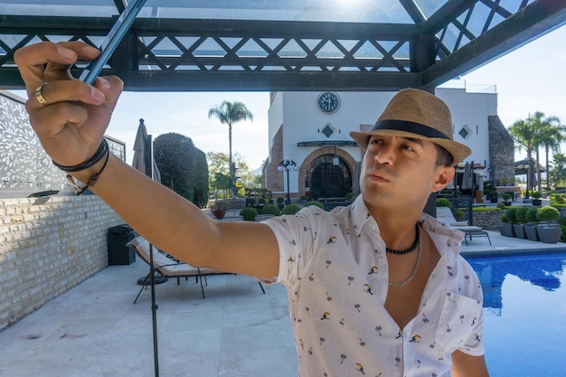 Un hombre hispano tomando un selfie junto a una piscina