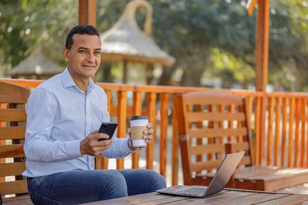 Hombre hispano usando una computadora portátil mientras toma café en un bar