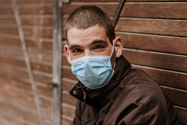 Foto hombre sin hogar al aire libre con máscara médica