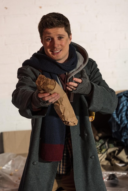 Hombre sin hogar con baguette de pan en la mano estirada