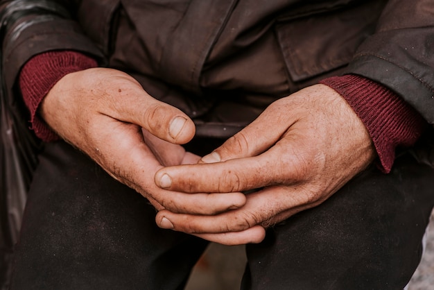 Hombre sin hogar sosteniendo sus manos