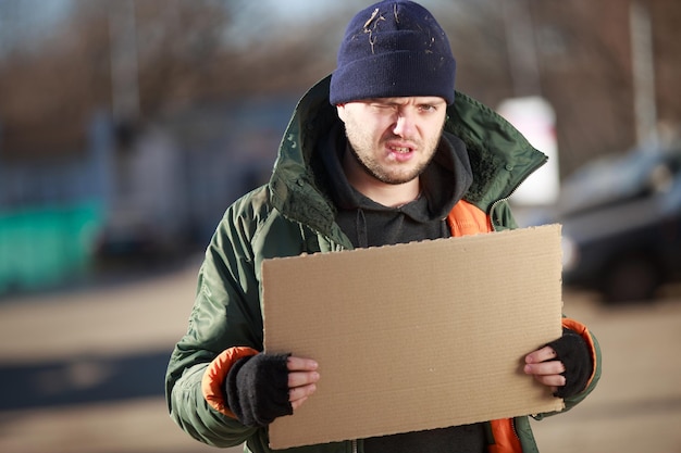 Hombre sin hogar tiene cartón en blanco para su propio texto