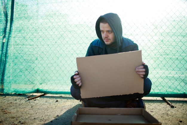 Hombre sin hogar tiene cartón en blanco para su texto