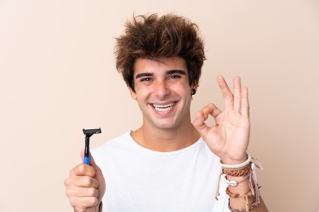 Hombre con hoja de afeitar sobre pared aislada