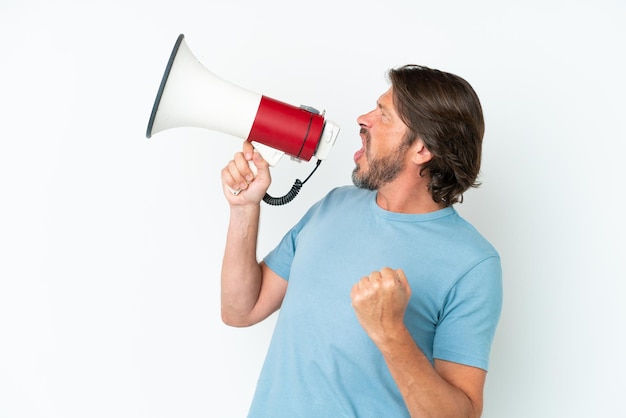 Hombre holandés senior aislado sobre fondo blanco gritando a través de un megáfono para anunciar algo en posición lateral