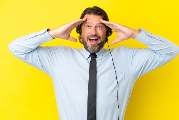 Hombre holandés telemarketer trabajando con un auricular aislado sobre fondo amarillo con expresión de sorpresa