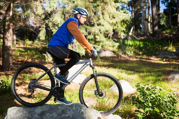 Hombre hombre ciclista de montaña montando bicicleta en el bosque